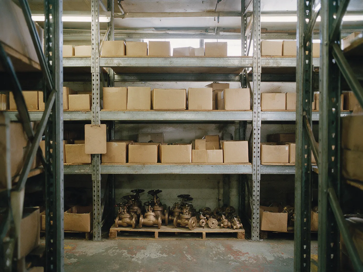 Warehouse racking holding cartons of valve stock, bronze and flanged valves palletised below